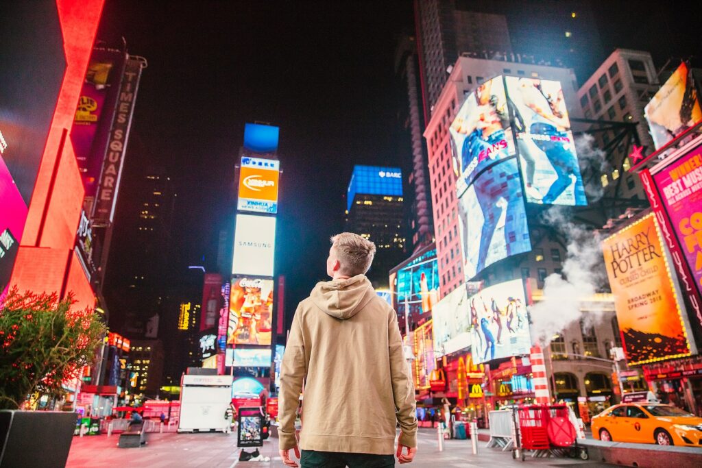 Un homme regarde les nombreuses publicités lumineuses affichées sur les façades de grands buildings